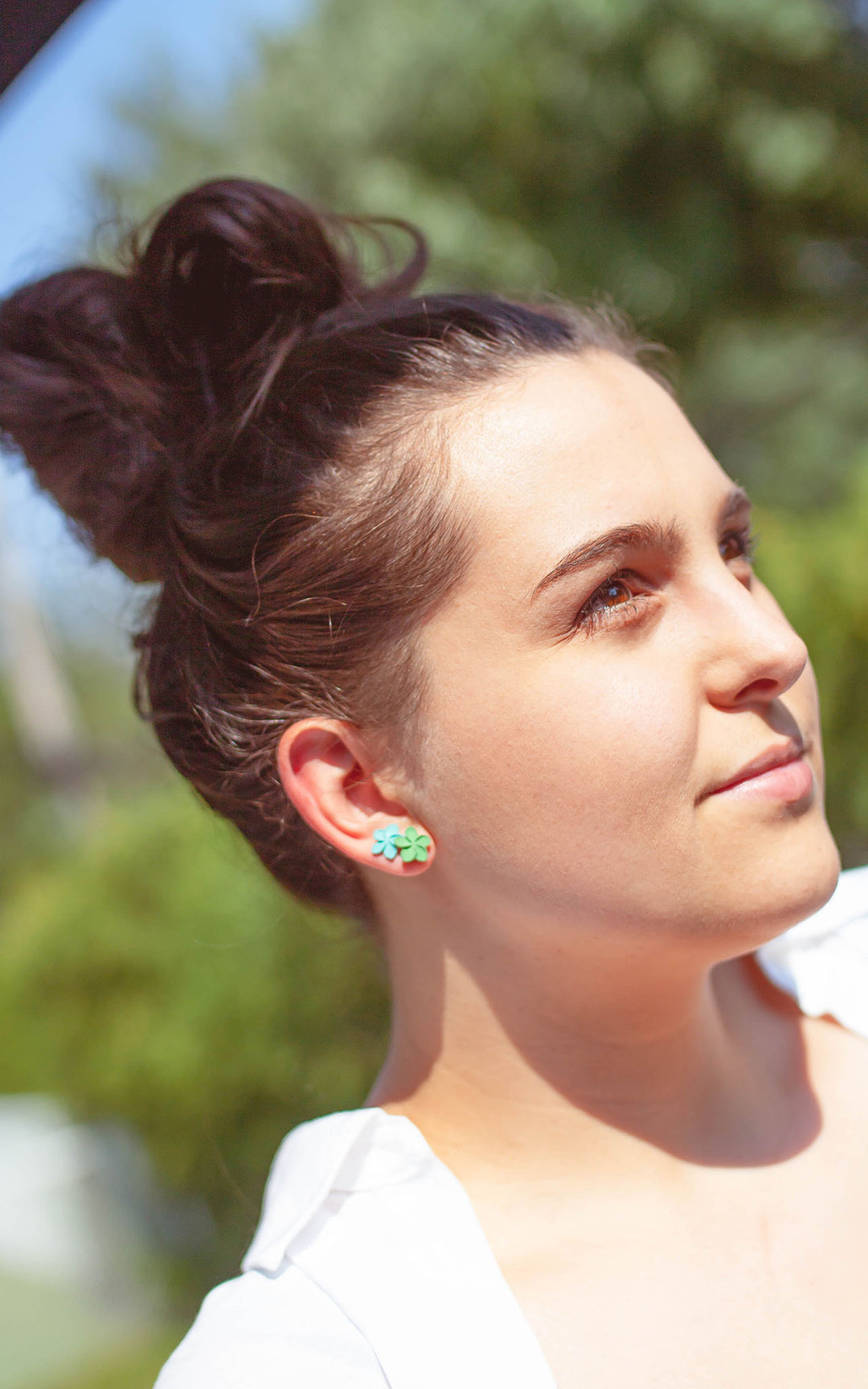 Femme portant les boucles d’oreilles OHANA, fleur de plumeria blanche en bijou 3D, look tropical et élégant