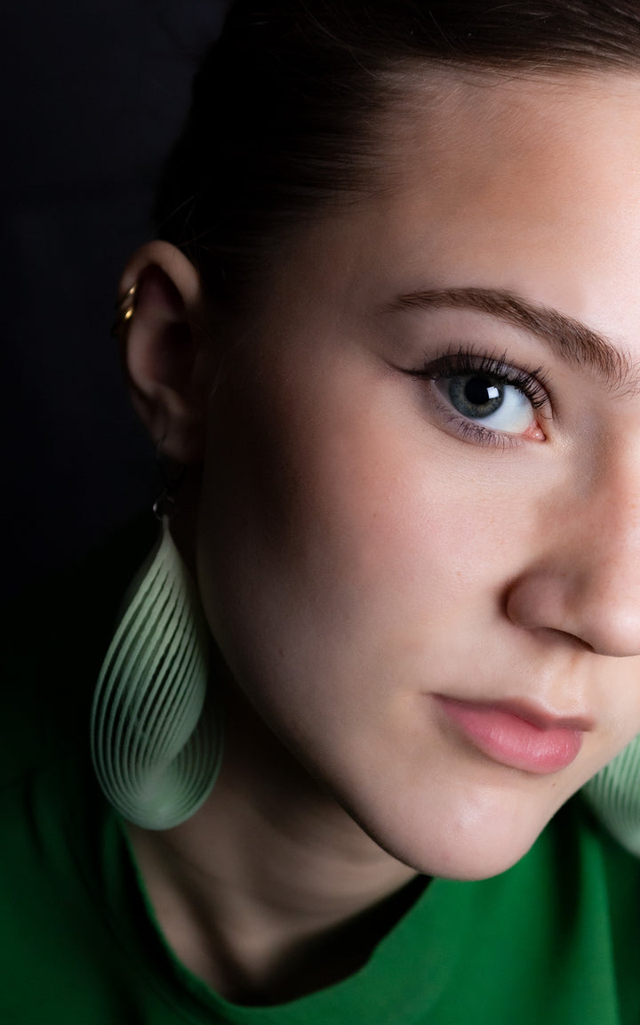 Portrait d’une femme portant les boucles d’oreilles OASIS vert sauge ultralégères en nylon recyclé imprimé 3D par Vox &amp; Oz