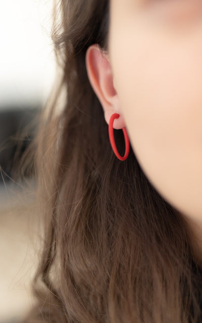 Jeune fille avec boucles d'oreilles rouges, bijou rouge, petit anneau d'oreilles rouge porté à l'oreille.