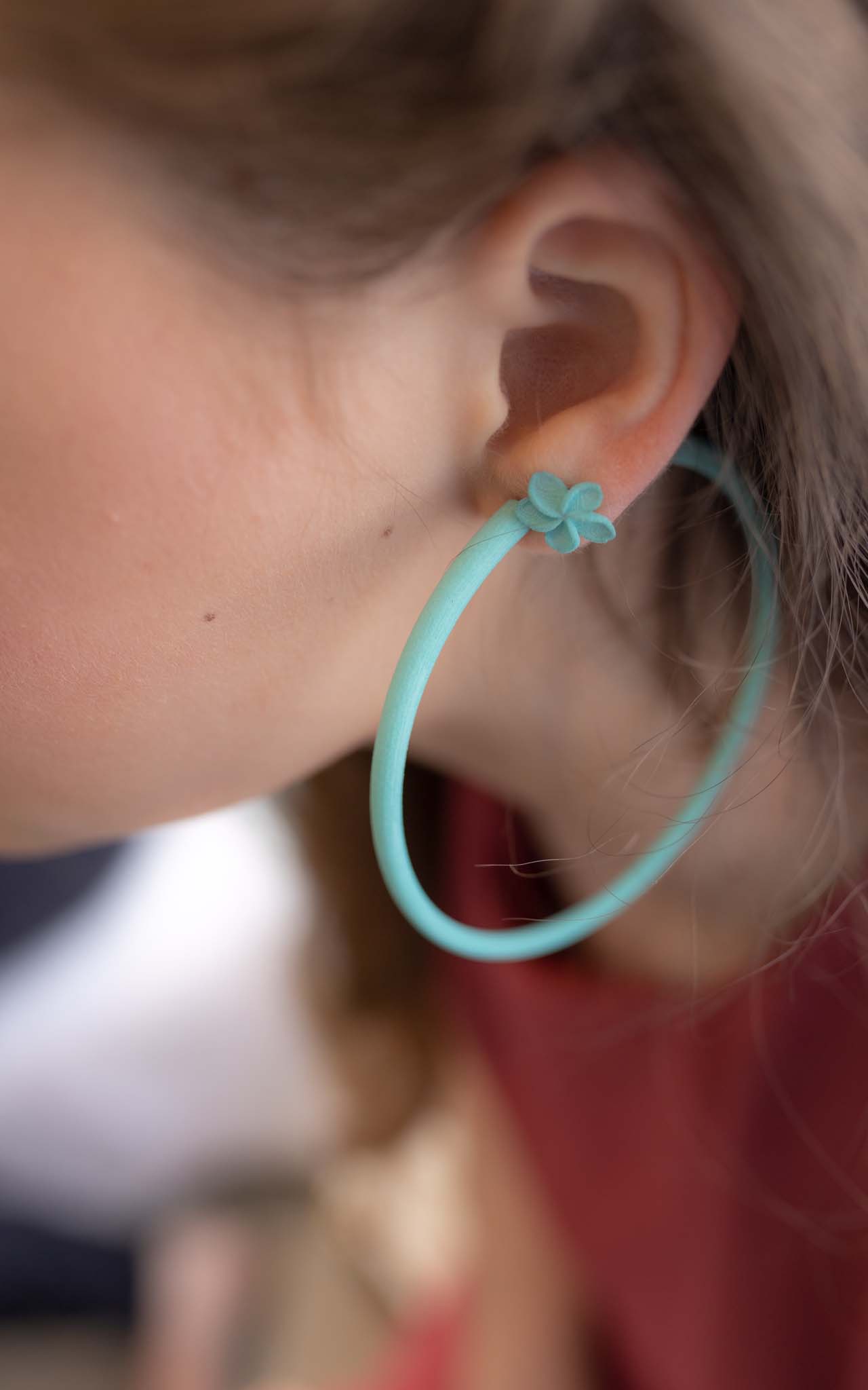 Les anneaux Atlas 8 cm jeune femme porte un anneau à l'oreille.. Couleur turquoise