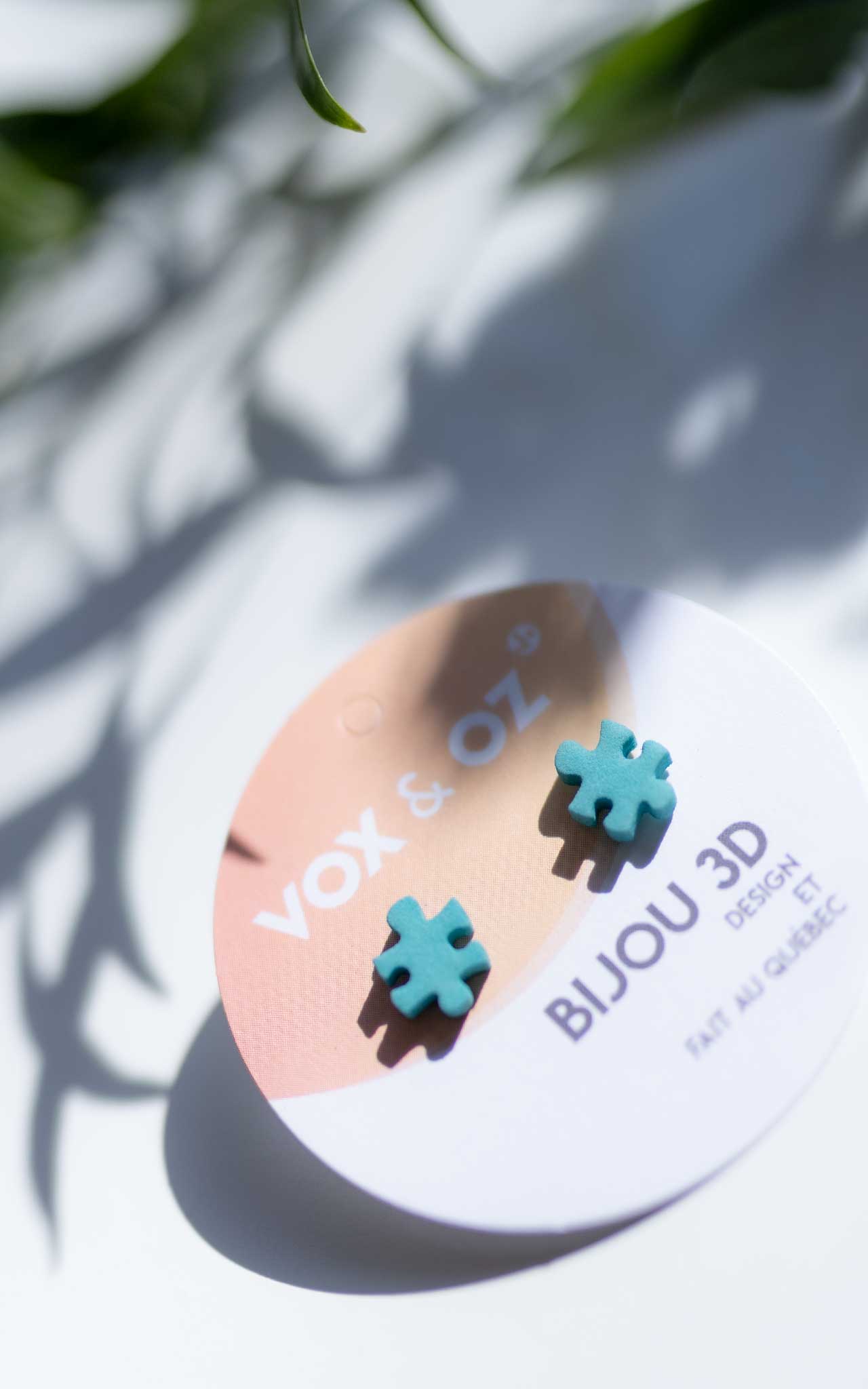 Boucles d,Oreilles en forme de casse-tete, sur une carte de la marque VOx & Oz. Le bijou est de couleur Sarcelle et est trèes attrayant sur cette charmante journée lumineuse d'été. 